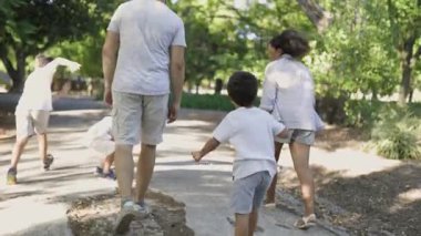 Park yolunda kameradan uzaklaşan bir aile.