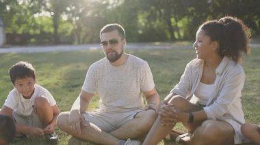 Mutlu aile güneşli bir parkta rahatlıyor ve birlikte oynuyorlar.