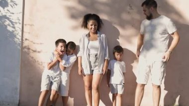 Aile duvarda birlikte poz veriyor, gülüyor ve eğleniyor.