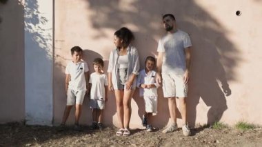 Duvara karşı bir resim için poz veren çok ırklı bir aile.