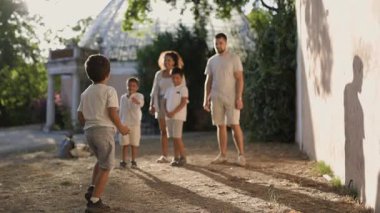 Parkta ailesiyle kurbağa oyunu oynayan genç bir çocuk.