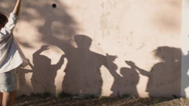 Mutlu aile, gölgeleriyle bir duvara yansıyarak oynuyor.
