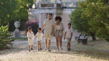 Mutlu bir aile parkta yürüyor, ebeveynlerin iki oğlu var.