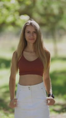 Parkta kameraya doğru yürürken gülümseyen güzel beyaz bir kadının portresi.