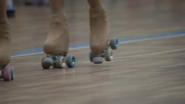 İnsanların bacaklarının ve ayaklarının ahşap bir buz pateni pistinde paten kayışının yakın görüntüsü.