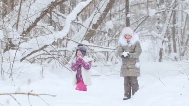 Kış ormanı İki küçük kız kar yağdırıyor. Orta çekim