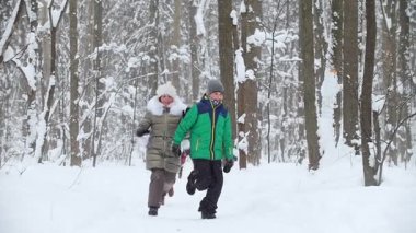 Kış ormanlarında küçük çocuklar birbirini takip ediyor. Küçük bir kız karda kardeşini deviriyor. Orta çekim