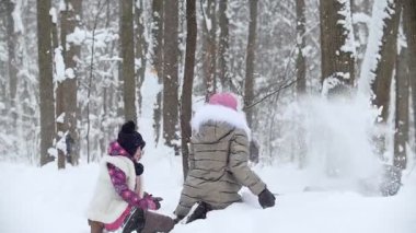 Kış ormanı İki küçük kız, küçük kardeşlerinin üzerine kar atıyor. Orta çekim