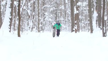 Kış ormanlarında küçük çocuklar birbirini takip ediyor. Orta çekim