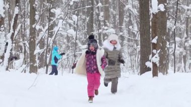 İki küçük kız kış ormanında koşup kartopu oynuyorlar. Orta çekim