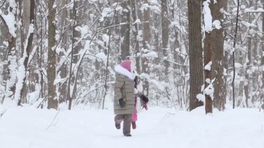 İki küçük kız kış ormanında kartopu oynuyor. Orta çekim