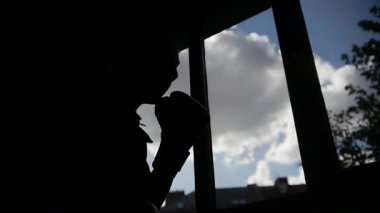 Adamın silueti pencerenin önünde dövüş egzersizleri yapıyor, ağır çekimde.