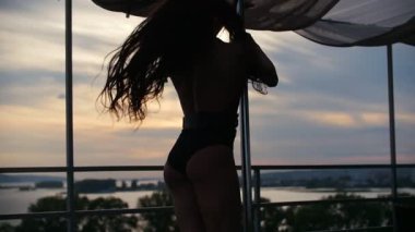 Açık havada dans eden genç ve güzel bir dansçı kız. Direk dansı, silüet yavaş çekim, gökyüzünün önünde.