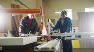 Marangozlar mobilya fabrikasındaki elektrikli testerenin ahşap detaylarını kesiyorlar.