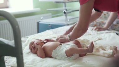 Doğum hastanesinde yeni doğmuş bir bebek. Hemşire bebeği kundaklıyor.