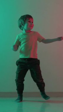 Genç çocuk neon ışıkta enerjik hareketlerle dans ediyor