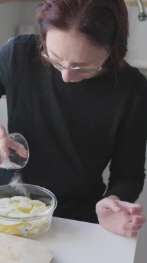 Kadın, ev mutfağında cam kasede dilimlenmiş patates pişiriyor.