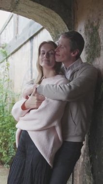 Sevgi dolu bir çift, bir kale kemerinde kucaklaşıyorlar, romantik bir anın tadını çıkarıyorlar.