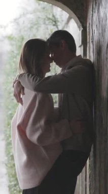 Yağmurdan korunan tutkulu çift, eski bir kemer yolunun altında hassas bir anı paylaşıyor.