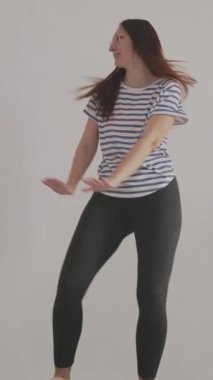 Kadın dans hareketleri yapıyor, kendini projektörle kaydediyor.