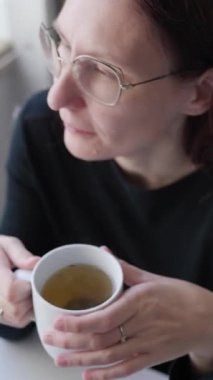 Mutfakta çay içen bir kadın.