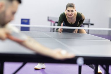 Evde oynanan masa tenisi maçında servis yapmaya hazır odaklanmış bir kadın.