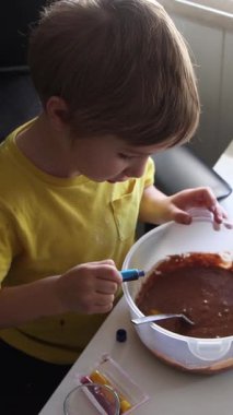 Çocuk, pasta ya da tatlı niyetine çikolata malzemelerini dikkatlice karıştırıyor. Bu da erken aşçılık merakını gösteriyor.