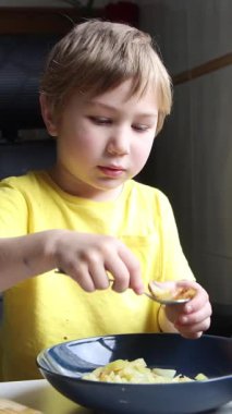 Sarışın çocuk tabletten video izlerken öğle yemeğinin tadını çıkarıyor.