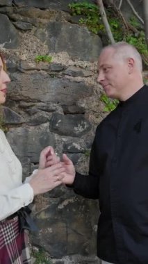 Madeira, Portekiz 'deki taş bir duvarın yanında el ele tutuşup birbirlerine bakan romantik bir çift.