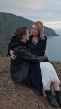 Okyanusa bakan bir uçurumda romantik bir anın tadını çıkaran genç bir çift.