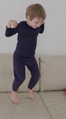 Küçük çocuk rahat bir kanepede zıplayıp zıplamaktan hoşlanıyor.