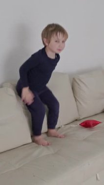 Kanepede kırmızı yıldız şekilli balonlarla oynayan mutlu çocuk.