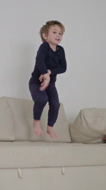 Neşeli çocuk atlıyor ve rahat bir kanepede eğleniyor.