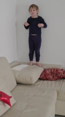Kanepe yastıklarında dikkatli bir şekilde dengede duran oyuncu çocuk.