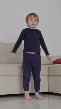 Enerjik çocuk oturma odasındaki kanepede dans hareketleri ve oyunlar uydurur.