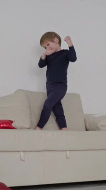 Enerjik çocuk koltukta dans ediyor, neşeli hareketler ve ifadeler sergiliyor.