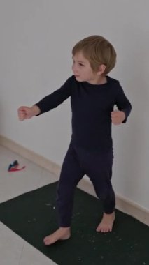 Enerjik çocuk evde yoga minderinde dans alıştırması yapıyor.