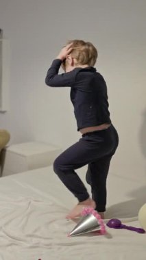 Pijamayla yatakta dans eden mutlu çocuk.