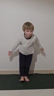 Genç çocuk yoga minderinde dans adımları atıyor.