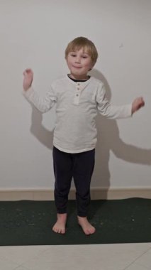 Yoga minderinde dans eden çocuk, beyaz bir arka planda izole edilmiş.