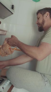 Sakallı adam, mutfakta bütün bir çiğ tavuğu kesme tahtasında hazırlıyor.