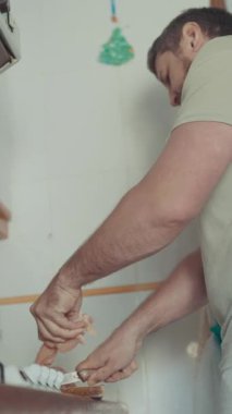 Günlük kıyafet giyen bir adam mutfak tezgahında ekmek keser.