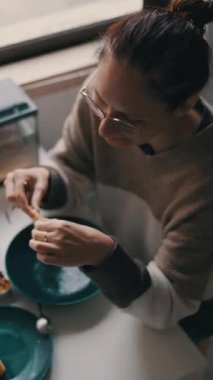 Evcil bir mutfakta elma soyan ve sağlıklı bir salata hazırlayan genç bir kadın.