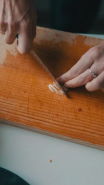 Sarımsak ince ince doğranmış tahta üzerinde bir kase doğranmış sebzenin yanında.