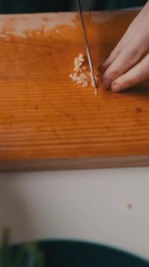 Ahşap kesme tahtasına sarımsak doğrayan şeflerin ellerini kapatın.