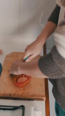 Kadın domatesleri ahşap bir kesim tahtasıyla dilimliyor, yerli bir mutfakta sağlıklı bir yemek hazırlıyor.