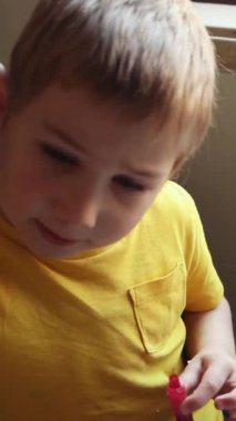 Renkleri kırmızı ve yeşil renklerle karıştırıp rengarenk karışımlar yapan meraklı çocuk.