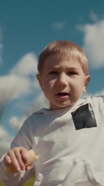 Genç bir çocuk güneşli bir günde elinde metal bir merdivenle muzdan zevk alıyor.