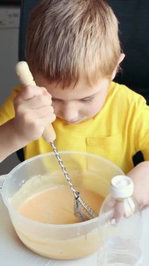 Çocuk çanakta malzeme çırpıyor, yemek yapmayı öğreniyor.