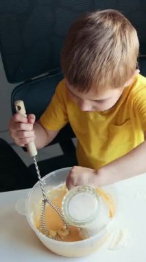 Çocuk tarifi takip ederek yemek yapmayı ve malzemeleri kaseye koymayı öğreniyor.